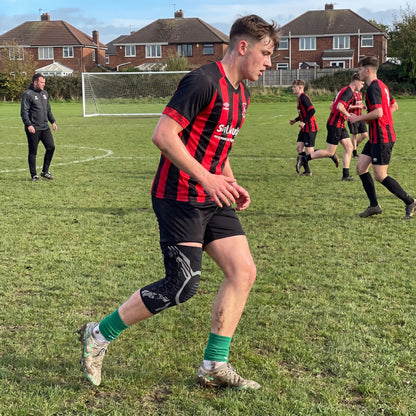 Footballer training with adjustable knee brace